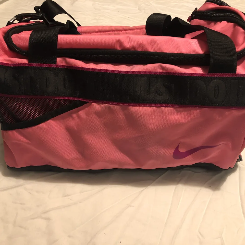 Rosa Nike väska, prefekt för gym eller sport. Köpt för ett par år sen och använd ett fåtal gånger. Finns ett fack på sidan för skor och en liten ficka på insidan för ex. Telefon, har vissa småfläckar.                                               Storlek: 44cm lång och 25cm bred. . Väskor.