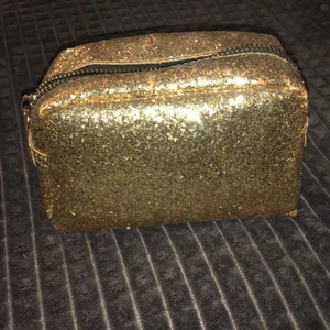 Sminkväska  - Guld sminkväska från lindex. Använd några få gånger men inget man märker på väskan. Köparen står för frakten.