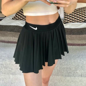 Nike tenniskjol - Säljer denna väldigt populära tenniskjolen med inbyggda skjorts från Nike. Den är i nyskick. Storlek L barn, men den sitter som en vanlig XS/S. Midjan mätt rätt över: 34 cm. Längd: 31 cm. Skickas spårbart med PostNord för 51kr. Första två bilderna är lånade