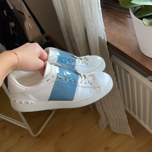 Valentino open sneakers - Ett par valentino open sneakers med blå rand. I super fint skick och knappt använda. Kommer med dustbag o extra skosnören! Äkthetsbevis finns. Kan skicka fler bilder vid intresse. Buda från 2200 kr eller köp direkt för 2800. Nypris är ca 5000 kr💙💙 storlek 37 men passar även en 36 eller 38 skulle jag säga.