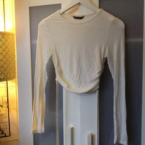 En vit tröja från Shein med detaljer och snören längst ner på tröjan som man kan knyta. 