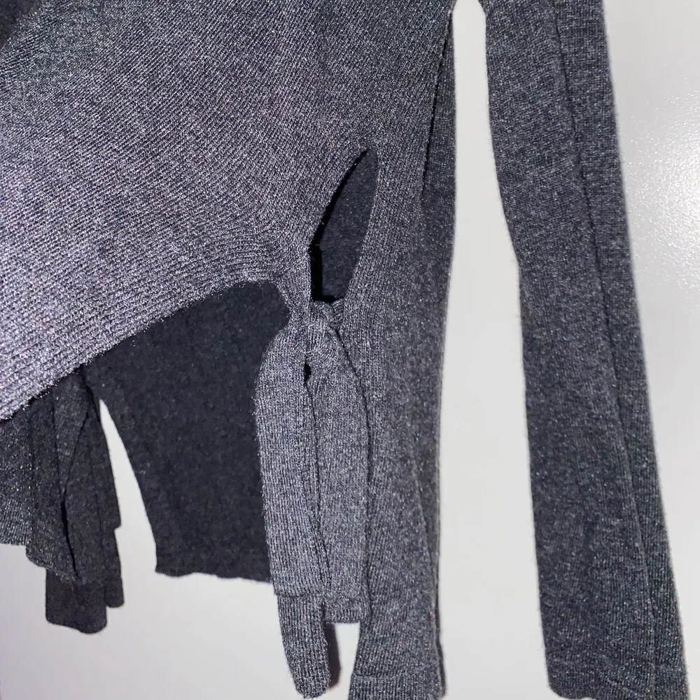 Marinblå stickad tröja med knytband på sidorna i storlek XS. Den är lite svår att få på bild men den är mörk marinblå/grå och den är även oanvänd så nyskick!. Stickat.