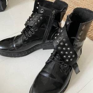 Kängor med nitdetaljer - Kängor från märket Tamaris som är använda ett fåtal gånger. Glansigt ”skinn”material. Inköpspriset var 800 kr. Köparen står för frakten