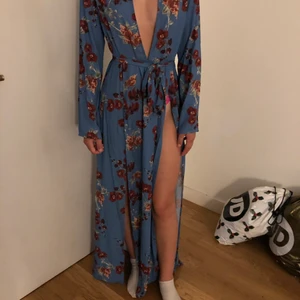 Klänning  - En blå blommig klänning från NA-KD i stl 36 den är aldrig andvänd och lappen sitter även kvar det finns två slitsar på båda sidorna av klänningen.