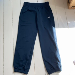 Nike mjukisbyxor  - Mjukis-/träningsbyxor från Nike. Materialet är syntetiskt så det funkar bra att träna i. Passformen är som XS och de sitter  ner till ankeln på mig som är 163 cm. Det finns justerbara band i midjan! Aldrig använda! Säljer för de nt kommer till användning :)