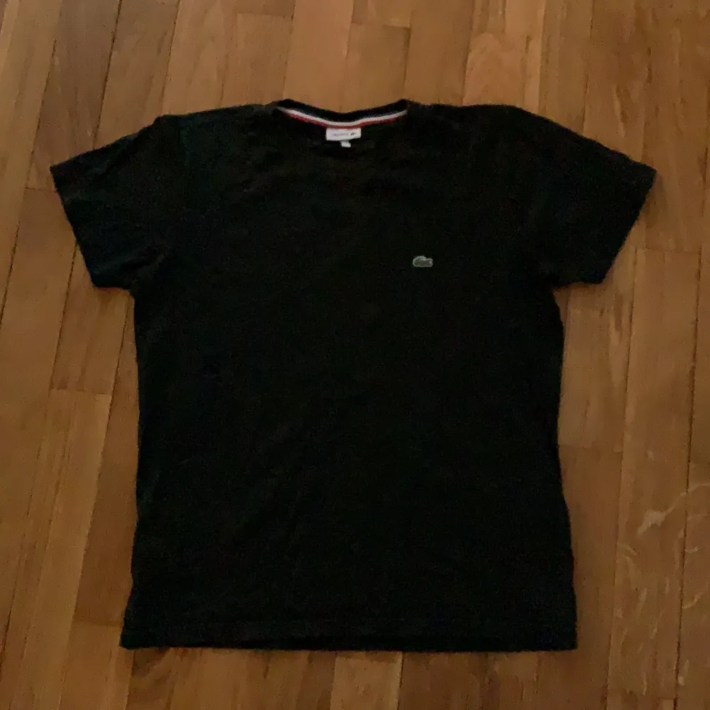 En svart Lacoste t-shirt använd typ inget . T-shirts.