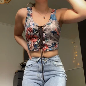 Crop topp med snörning - Superfin blommig linne/topp med snörning framtill ifrån Fashionnova. Toppen är i stl. M men passar till både större och mindre med hjälp av den skjusterbara snörningen. 🌺