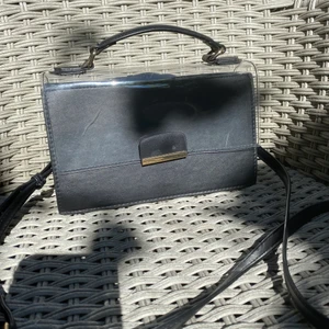 Axelremsväska bästa svart - Rymlig axelremsväska med genomskinlig del. Liten repa på den men utöver det i nytt skick. 