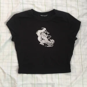 Svart t-shirt med tryck - Det här en superfin svart tight tröja med en vit drake tryckt på. Tröjan är köpt från SHEIN för nåt år sen. Använd få gånger💓 Storleken är XS men passar XXS-S💕 40kr + 30kr frakt💞