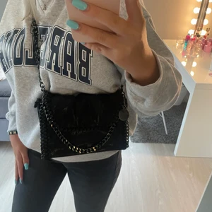 Stella Macartney liknande väska  - Säljer denna svart lite glittriga väskan, den är inte en äkta Stella väska men liknande bandet är lite längre än på bilden jag har stoppat in bandet lite, ni står för frakt💕högsta budet 350 + 66kr frakt 