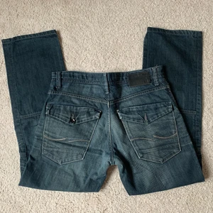 Jeans med detaljer - Säljer dessa coola jeans men unika detaljer i storlek W33, 87cm midja och 77cm innerbenslängd! Jag på bilderna är 172cm lång och brukar ha storlek 38/W28/S-M❤️ OBS! En knapp på ena bakfickan saknas, syns på bilderna💕