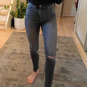 Jeans i stretch i grå färg från bikbok med hål i knäna och ”slitna detaljer” i byxslutet. Strl xs. Köparens står för frakten.