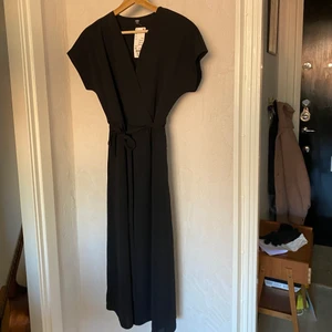 Klänning från Uniqlo  - Svart fin omlottklänning från uniqlo. Omlott-formen är fastsydd med löst band till. Storlek xs, oanvänd, prislapp kvar. Nypris 349kr. Köparen står för frakten. 