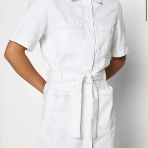 Vit jeansklänning - Jeansklänning med fickor och knyte i midjan. Superfin till studenten, använd endast 1 gång.