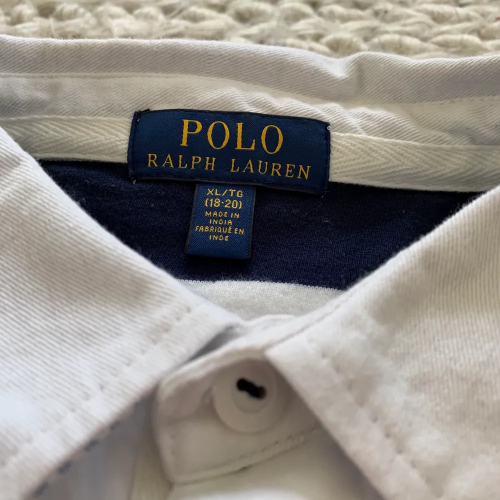En Polo Ralph Lauren långarmad i stl 164. Den är vit och blå med ett litet rött tryck. Den är i väldigt bra skick och köptes på NK 2019. Tröjor & Koftor.