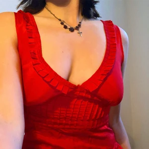 Rött linne - Rött linne med fina ”räfflade” detaljer vid bysten och urringningen. Är i siden. Liten dragkedja vid sidan som inte syns men den gör att den sitter perfekt. Det står storlek 32 men passar mig som har 36/38.