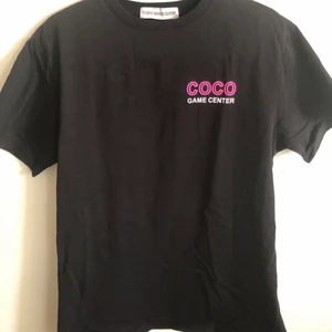 Unisex Chanel Coco Game Center Tee - Unisex Chanel Coco Game Center T-Shirt  Size medium, men’s regular medium fit.  Excellent condition, no flaws or damage.  DM if you need exact size measurements.   Buyer pays for all shipping costs. All items sent with tracking number.   No swaps, no trades, no offers. 