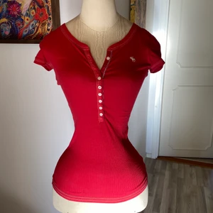 Abercrombie & Fitch T-shirt  - Röd fin T-shirt från Abercrombie & Fitch i storlek XS. En knapp saknas. 50kr eller högstbjudande 