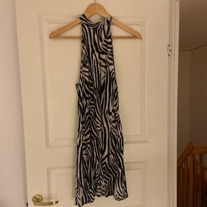 Zebra klänning - En super fin zebraklänning med knytdetalj i hals, inga ärmar och lår lång. Tunnare tyg så perfekt till sommaren. Aldrig använd, topp skick. 