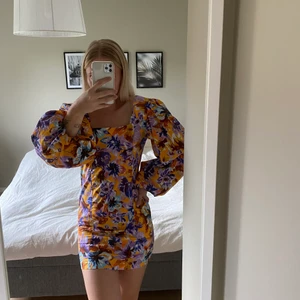 Blommig klänning - Blommig klänning med stora armar. Kortklänning.