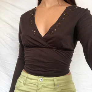 Brun wraptop med paljetter  - köp direkt för 150!!!!!! BUD ENDAST GILTIGT OM MAN ÄVEN HÖRT AV SIG PRIVATUnderbar unik brun wraptop med paljetter både vis urringning och ärmslut. Kan knytas i ryggen för att dras åt. På första bilden är den uppknuten men går lätt att croppa. Köpare står för 48kr frakt 