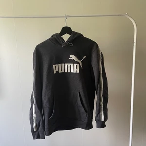Puma-Hoodie - En hoodie från puma med ett logotyp revär på ärmarna. Frakt fastslås vid bestämmelse, köpare står för frakten.