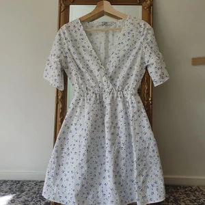 Na-kd klänning - Vit klänning med blå små blommor från na-kd. Endast använd en gång på skolavslutnings så i väldigt fint skick. Passar mig som har xs-s. Pris kan diskuteras! <33