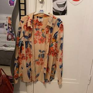 En beige skjorta med blommor och fåglar på. Köpt på Lindex- Holly & Whyte. Storlek M. Knappast använd, fint skick.