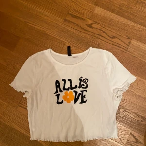 Tröja/linne - En vitt tröja/linne med tryck på framsidan. Har räfflor typ på armarna och nedre delar av tröjan/linnet.☺️kommer från H&M .