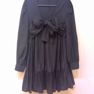 Svart vollangklänning med rosett - Superfin klänning med knytbar rosett. Använd en gång. Prasslar bra till fest! Från zara förra vintern.