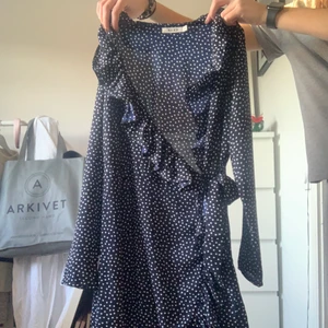 Prickig klänning med volang - Mörkblå omlottklänning från NAKD. Endast använd ca 2 gånger av mig, som ny!