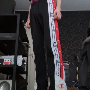 Champioan track pants - Champion trackpants med knappar på sidorna. Dem är i Storleken me men midjan är väldigt elastisk så dessa passar nog de flesta! 