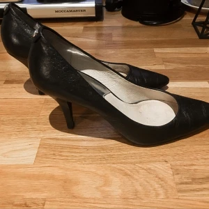 Michael kors pumps - Klassisk sko från Michael kors i äkta skinn i "mid high" Liten skada på ens klacken, se sista bilden.  Obs: strlk står 7M under skon vilket innebär ca strlk 38 men de är små i storlek så skulle säga strlk 37- 37,5 är mer korrekt. Frakt tillkommer.
