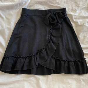 Svart kjol - Säljer denna jättefina kjolen från Gina Tricot. Köpte den i somras men har tyvärr bara använt den fåtal gånger. Väldigt fin med volanger och rosett på vänster sida. Perfekt längd! Skriv till mig privat för fler bilder om du är intresserad.