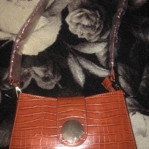 Väska  - Säljer denna oerhört snygga bruna väskan, fick den i födelsedagspresent i söndags och ni ser att plasten är kvar, pappret inuti är kvar osv.. de medföljer ju såklart ett längre ” handtag/band ” om man vill göra väskan längre. Den kostade runt 200kr