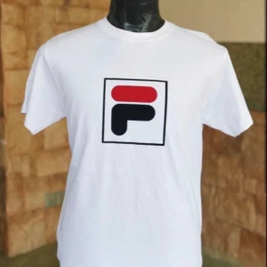 Vit Fila T-shirt  - En vit t shirt med fila loggan i mitten. Plaggets ärmar är uppvikta och uppsydda. Plagget har använts men inga fläckar eller hål. 50kr, frakt är ej inkluderad.