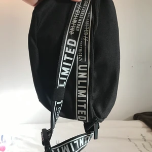 Magväska - Svart magvästa med textdetaljer, justerbart band och innerfack. Använd men i fint skick. 