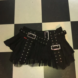 Kort alternativ kjol - Kort kjol med ett slags inbyggt bälte och korta hängslen. Den är storlek L men passar M. Aldrig använd och i nyskick. Köpt för 300 kr på second hand, men märket heter queen of darkness. Den är väldigt kort, så äe bra att ha shorts under!