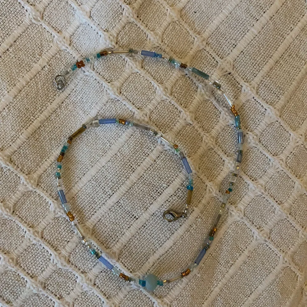Halsband med blå/ bruna pärlor och en ljusblå sötvattenspärla . Accessoarer.