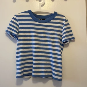 Randig T-shirt - En skön randig T-shirt som tyvärr inte kommit till användning. Endast använd ca 2 ggr. Ljusblåa ränder, passar både xs och s!