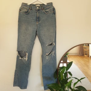 Highwaisted jeans med hål, stl 40 - Highwaisted jeans från Gina Tricot. Stl 40. Raka ben med hål på knäna. Frakt tillkommer.