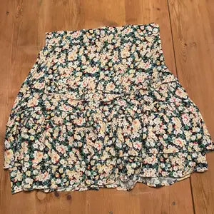 En super söt och snygg kjol i blommigt mönster. Aldrig använd. En dragkedja på sidan så det är smidigt att ta på. 