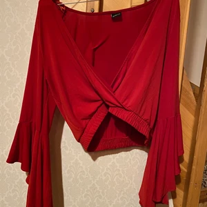 En röd blus med volanger i armarna ! Stl L - Har använt blusen 2 gånger bara och den är i bra skick ! Original priset : 250kr 