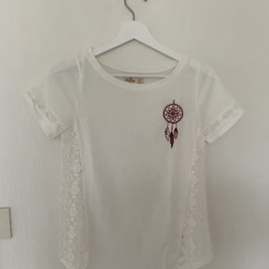 T-shirt, Hollister, Strl XS - Snygg T-shirt från hollister med spetsdetaljer på sidorna. I mycket gott skick 