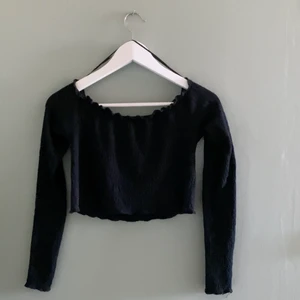 Off-shoulder topp  - Svart off-shoulder topp i ribbat material med detaljer av ”volanger” längs med kanterna. Köpt på BikBok och är använd ett fåtal gånger.