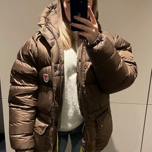 Fjällräven expedition down lite Strlk S - Såå fin Fjällräven expedition down lite jacka i brunt. Jättefin lyster i tyget! I väldigt fint skick, något färgpåverkad på de gula snörena. Nyligen kemtvättad. Även påsen som kommer med jackan ingår.