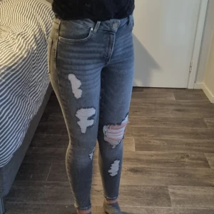 Grå högmidjade jeans med slitna detaljer - Grå högmidjade jeans med slitna detaljer, använda en gång. Sköna och sitter snyggt på kroppen. Storlek S. Lagom långa på mig som är 170cm. Från Bikbok, köpta för 600 kr. 
