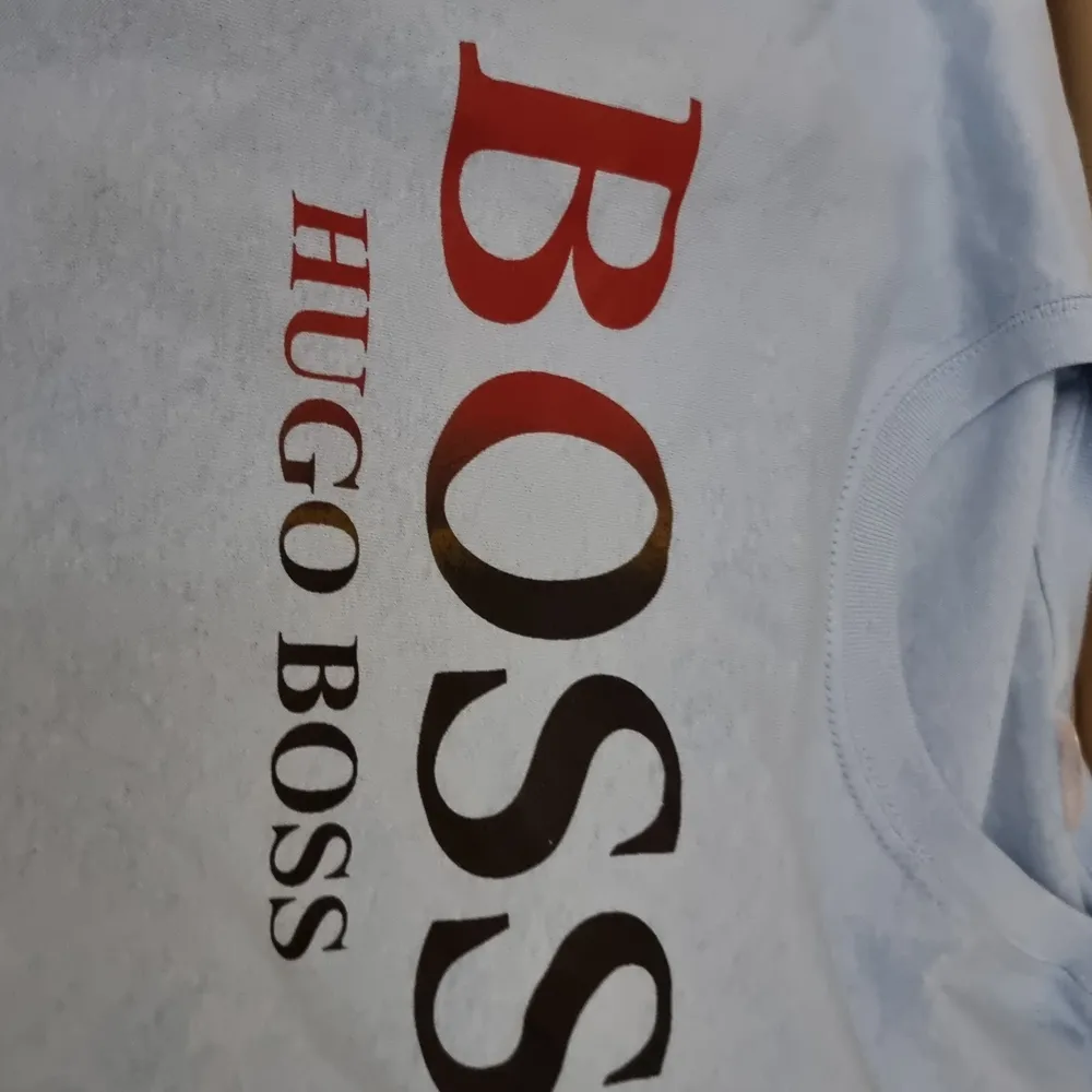 Oanvänd Hugo Boss t-shirt med centrerad text och ljusblå bakgrund. Simpel design funkar med det mästa. Framhäver dina armar och är väldigt behaglig att ha på sig.       (!Tar häldst swish!). T-shirts.