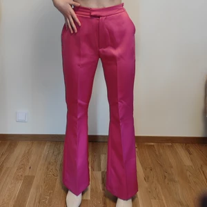 Kostymbyxor - Rosa färglagda kostymbyxor från Gina Tricot passar perfekt till vårens färgtrend! Utsvängda mot slutet vilket ger benen så finform. De är insydda på båda sidorna för att passa i midjan, men stygnen går lätt att sprätta upp. Mycket gott skick då det bara används ett par gånger