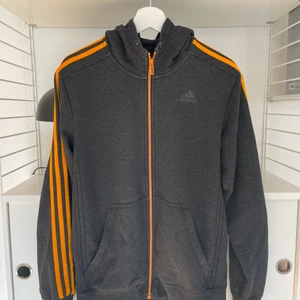 Hoodie Adidas  - Säljer nu min Adidas hoodie som är mörkgrå med orangea detaljer! 